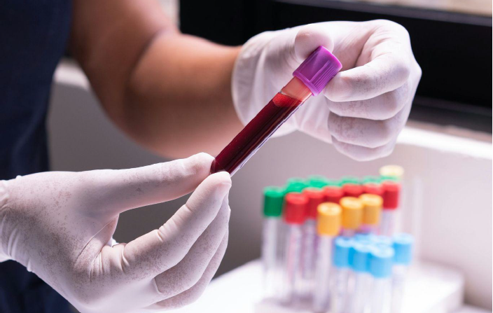 gloved hands holding a vial of blood